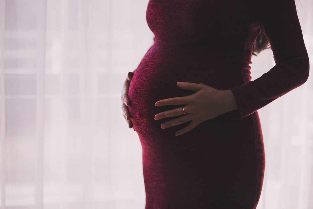 Cropped stock photo showing a pregnant person holding their belly